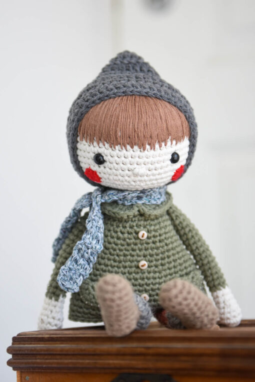 amigurumi doll in a coat and bonnet